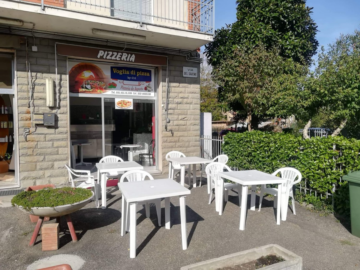 La pizzeria Voglia di Pizza by Cri in Via del Savena, con la tenda marrone e i tavolini all'aperto