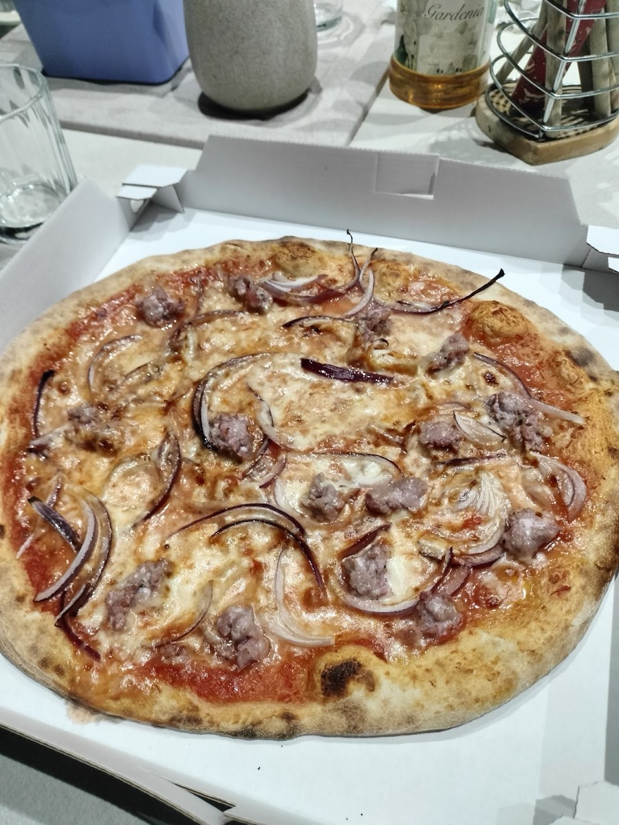 Pizza con salsiccia e cipolla appena sfornata nel cartone
